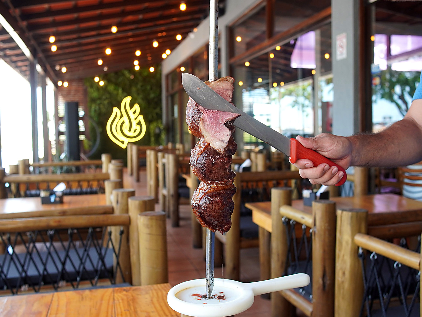 Espeto de picanha sendo fatiado no salão da Fogo & Brasa